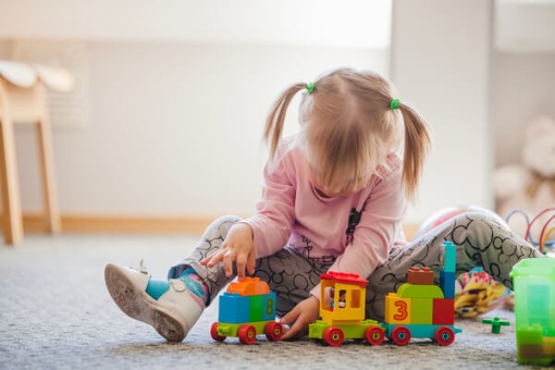 Niña de primera infancia jugando con un tren de bloques